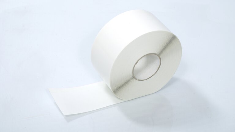 Ein weißes aufgerolltes Band Trennstreifen TrennfixPRO auf leicht blauem Hintergrund